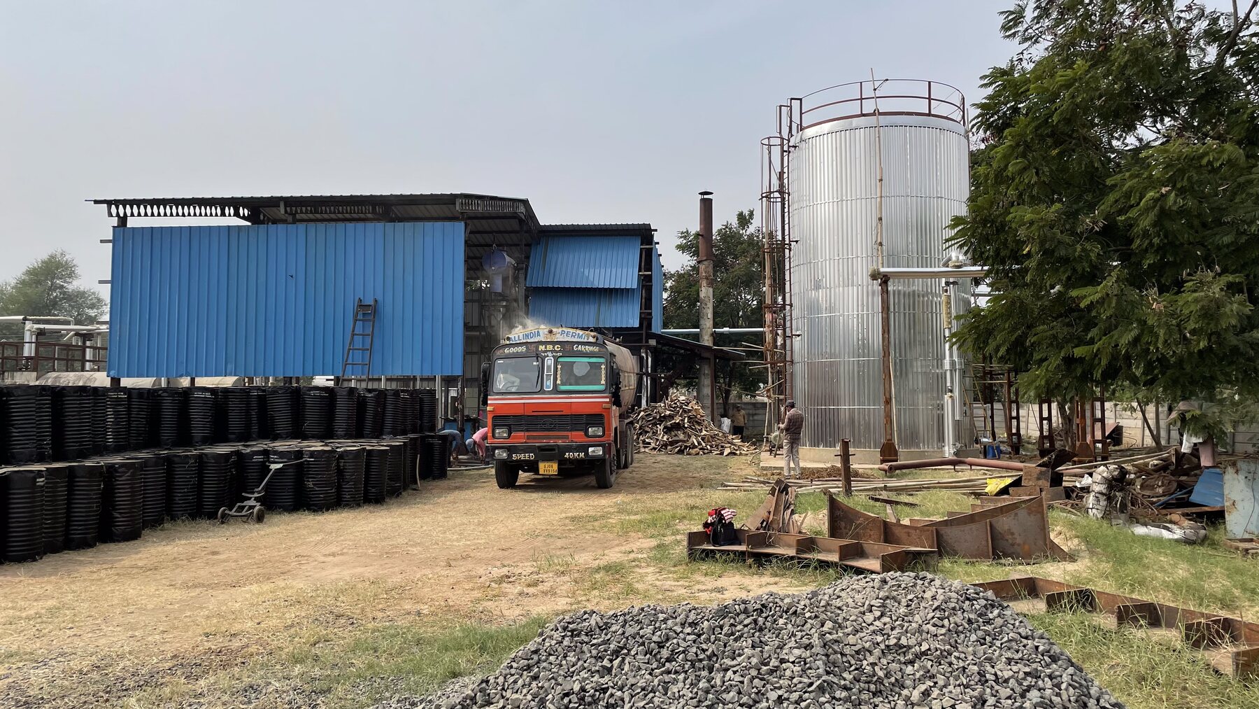 Industrial yard with storage tank, drums, and transport vehicle